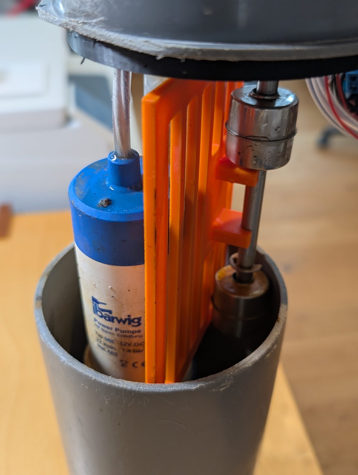 The prototype where the divider idea first appeared. This is the photo where the project stopped failing. The prototype internals — orange divider, pump and float switch inside the grey pipe
