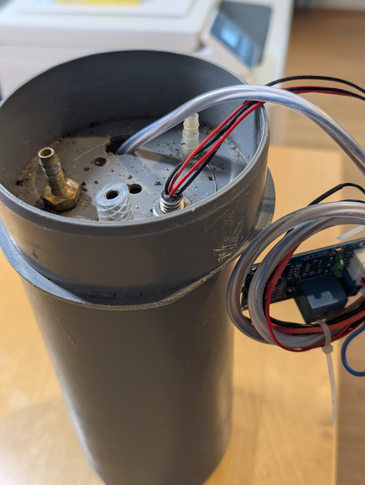 The prototype lid. Every one of those holes was, at some point, a leak. The prototype lid with brass hose barbs and cable glands